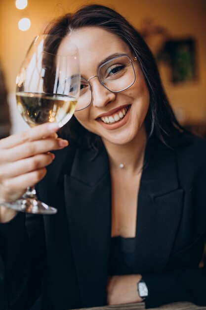 Mujer joven bebiendo vino blanco en un restaurante