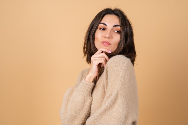 Mujer joven en beige en un suéter suave y acogedor con maquillaje profesional diurno lindo sonriendo