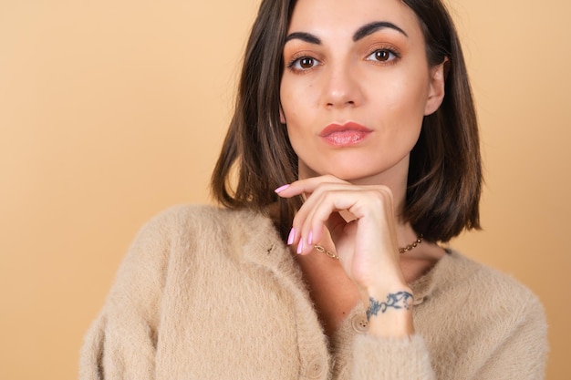 Mujer joven en beige en un suéter suave y acogedor con maquillaje profesional diurno lindo sonriendo