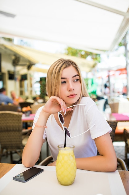 Mujer joven belleza con cóctel en street cafe