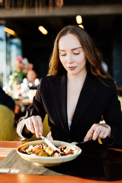 Mujer joven belleza comiendo alimentos saludables sentado en el hermoso interior con flores verdes