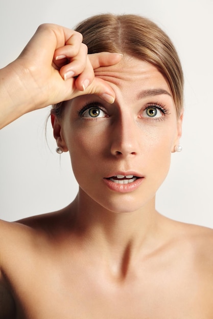 Mujer joven belleza preguntándose si tiene arrugas en la frente