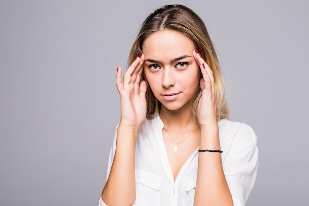 Mujer joven belleza tiene dolor de cabeza en una pared gris