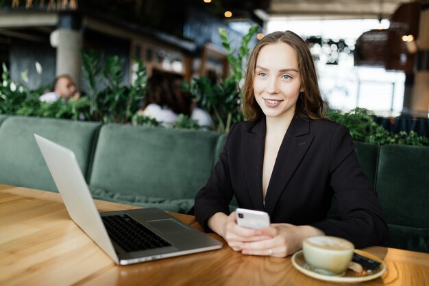 Mujer joven belleza trabajando en el portátil en la cafetería.