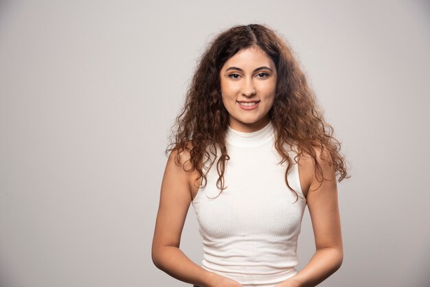 Mujer joven en blusa blanca de pie sobre una pared blanca. Foto de alta calidad