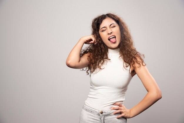 Mujer joven en blusa blanca de pie sobre una pared blanca. Foto de alta calidad