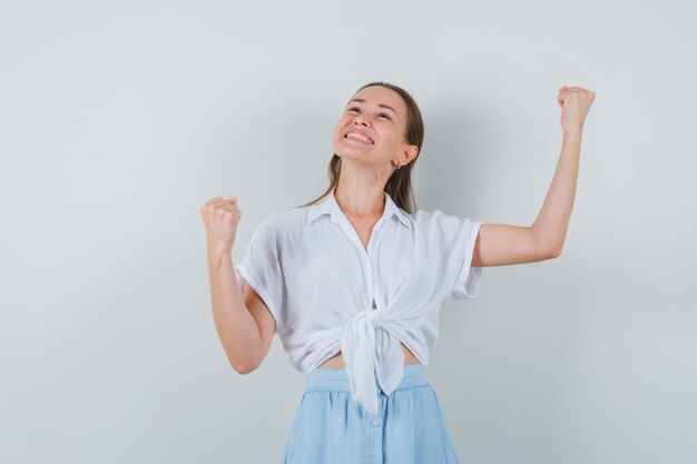 Foto gratuita mujer joven en blusa y falda mostrando gesto de ganador y con suerte