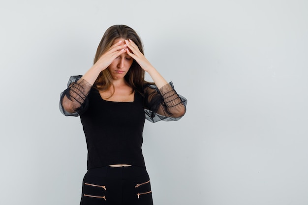 Foto gratuita mujer joven en blusa negra cogidos de la mano en la frente y mirando agotado