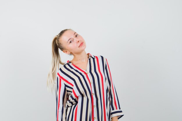 Mujer joven en blusa de rayas sonriendo y mirando feliz