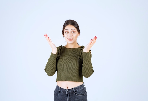 Foto gratuita mujer joven en blusa verde en busca de respuestas en la pared blanca