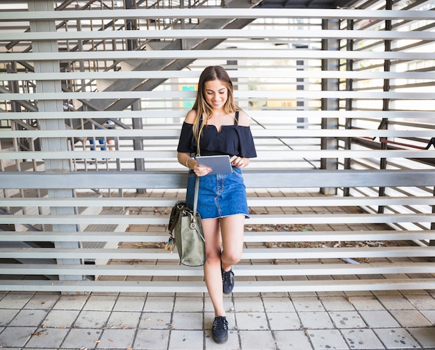 Mujer joven con bolsa con tableta en la Universidad