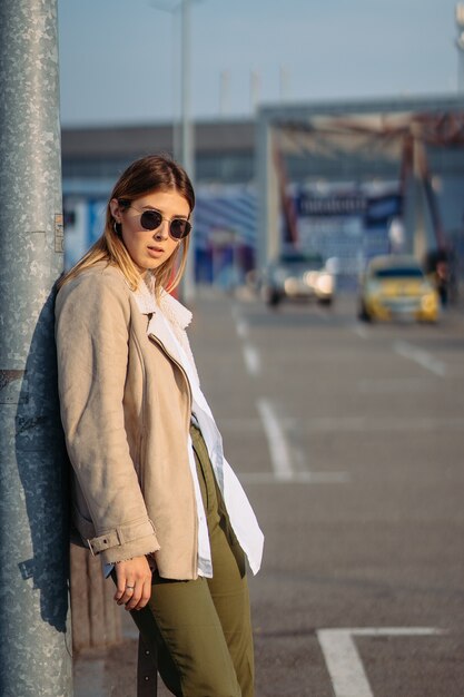 Mujer joven con bolsas de la compra en una parada de autobús posando