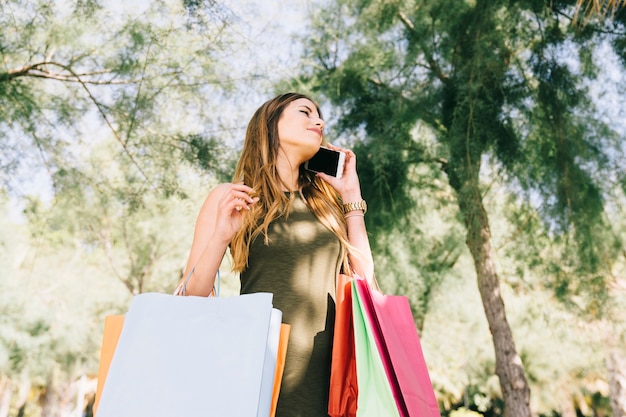 Mujer joven con bolsas de compras al teléfono