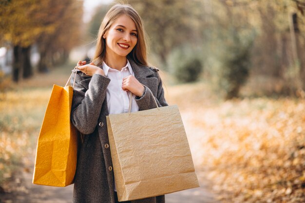 Mujer joven con bolsas de compras caminando en el parque