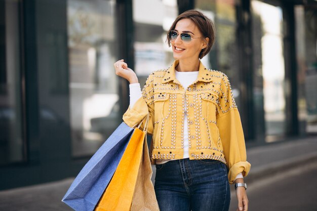 Mujer joven con bolsas de compras en la ciudad