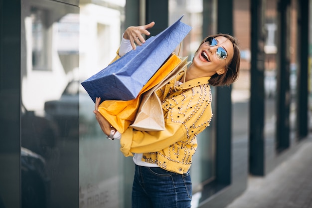 Mujer joven con bolsas de compras en la ciudad