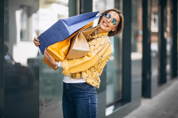 Mujer joven con bolsas de compras en la ciudad