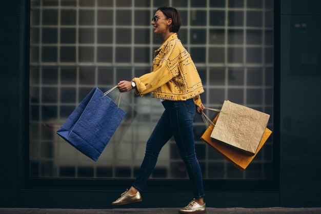 Mujer joven con bolsas de compras en la ciudad