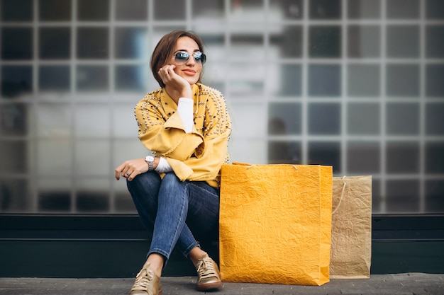 Mujer joven con bolsas de compras en la ciudad