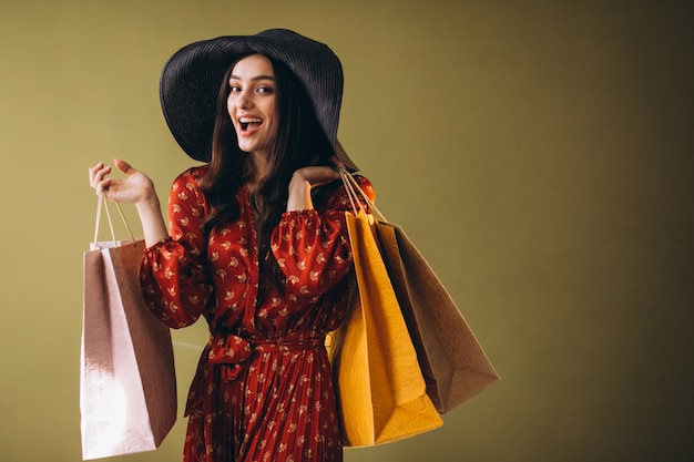 Mujer joven con bolsas de compras en un hermoso vestido y sombrero