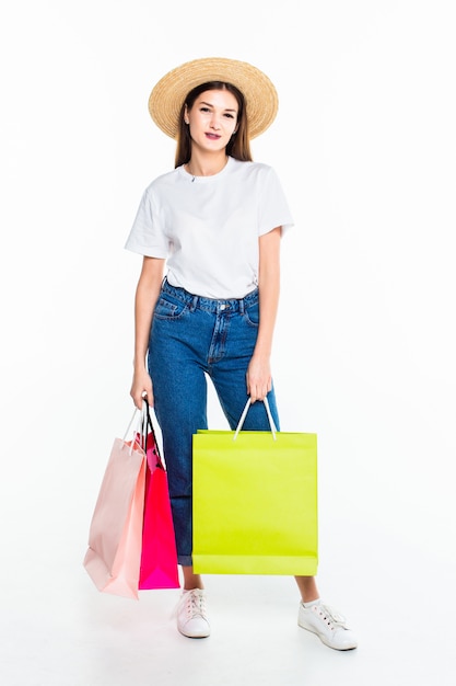 Mujer joven con bolsas de compras en la pared blanca