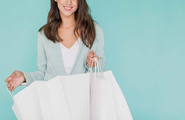 Mujer joven con bolsas de compras sobre fondo azul