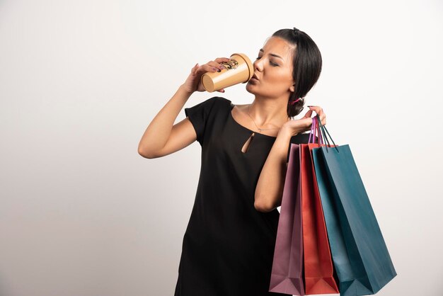 Mujer joven con bolsas de compras tomando café.