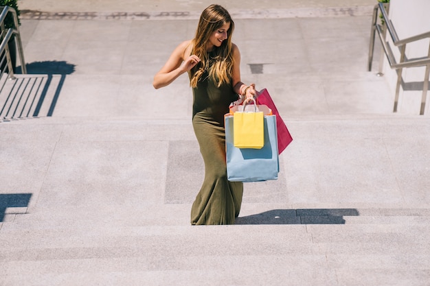 Foto gratuita mujer joven con bolsas sonriendo y subiendo las escaleras