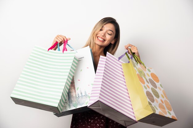 Mujer joven en bolsas de la tienda en la pared blanca.