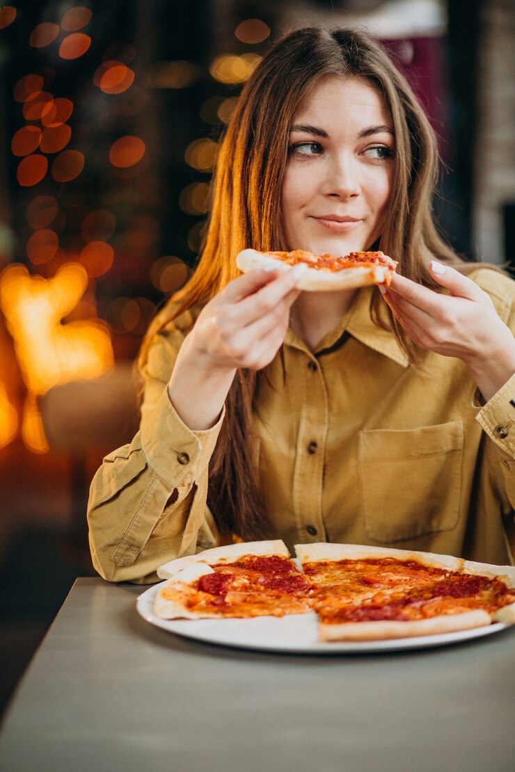 Foto gratuito una mujer joven y bonita comiendo pizza en un bar.