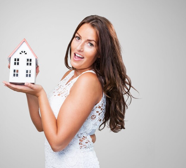 mujer joven y bonita que muestra un objeto de la casa