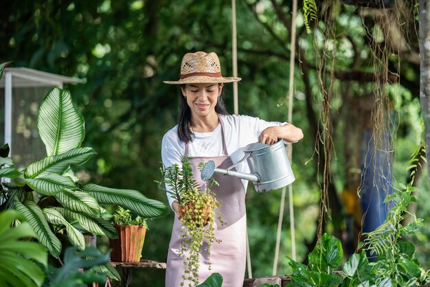 Mujer joven y bonita regar el árbol en el jardín en un día soleado de verano. mujer jardinería exterior en la naturaleza de verano. concepto de agricultura, jardinería, agricultura y personas.