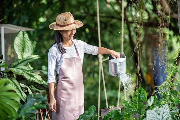 Mujer joven y bonita regar el árbol en el jardín en un día soleado de verano. mujer jardinería exterior en la naturaleza de verano. concepto de agricultura, jardinería, agricultura y personas.