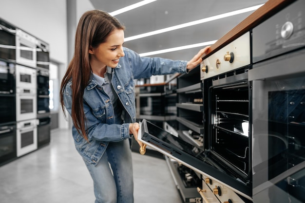 Mujer joven en busca de nuevo horno eléctrico en un centro comercial