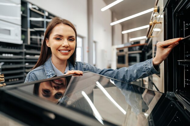 Mujer joven en busca de nuevo horno eléctrico en un centro comercial