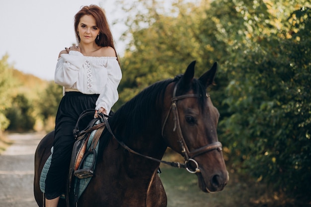 Mujer joven a caballo en el bosque