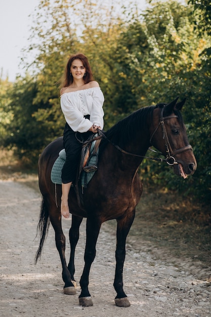 Mujer joven a caballo en el bosque