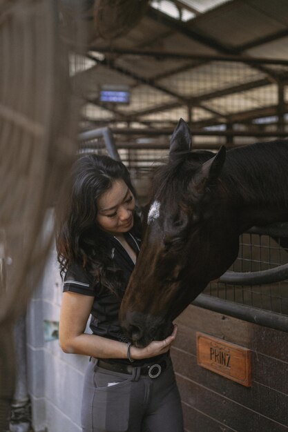 Una mujer joven y un caballo, sentimientos, cuidados, cariño, ternura, una mujer abraza y besa a un caballo. Cerca de una joven feliz abrazando a su caballo.