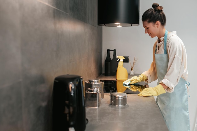 Foto gratuita mujer joven de cabello oscuro desinfectando las superficies en la cocina