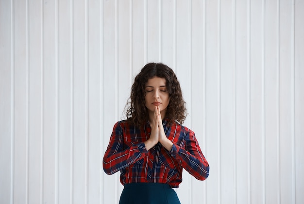 Foto gratuita mujer joven con cabello rizado y camisa a cuadros rezando