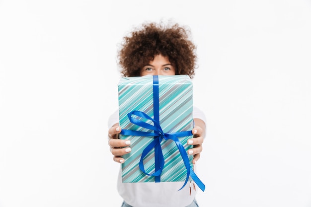 Mujer joven con cabello rizado mostrando caja de regalo