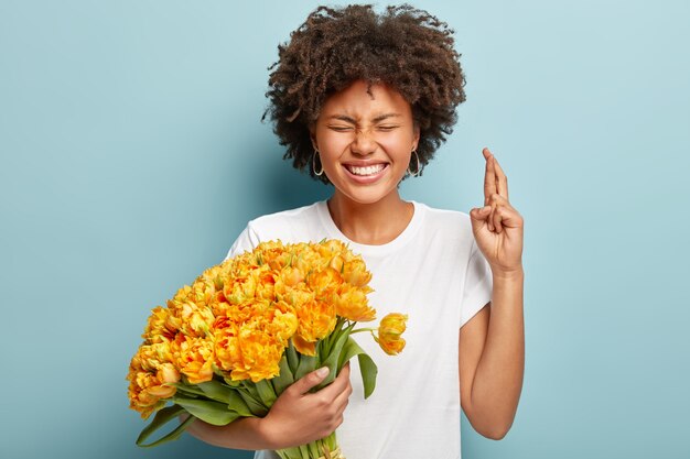 Mujer joven con cabello rizado con ramo de flores amarillas