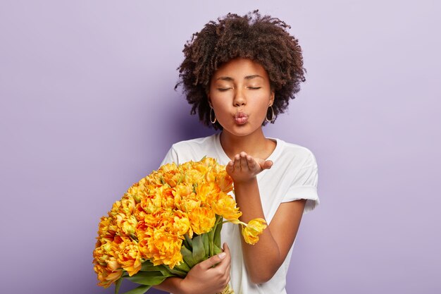 Mujer joven con cabello rizado con ramo de flores amarillas