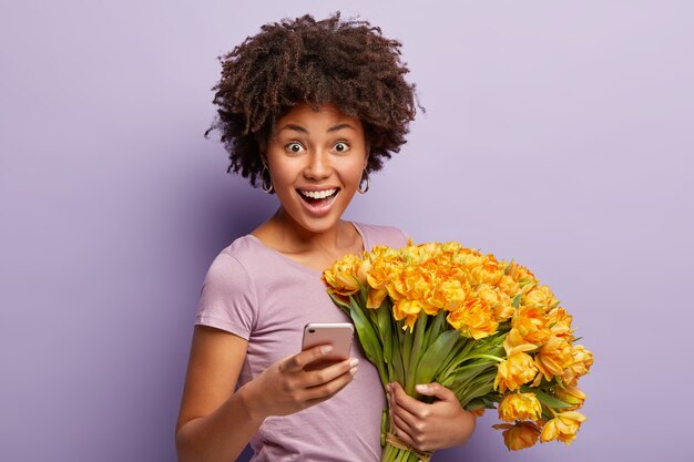 Mujer joven con cabello rizado con ramo de flores amarillas