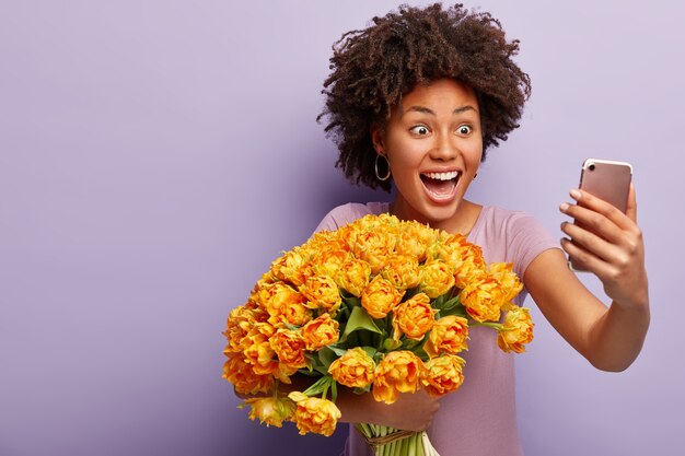 Mujer joven con cabello rizado con ramo de flores amarillas