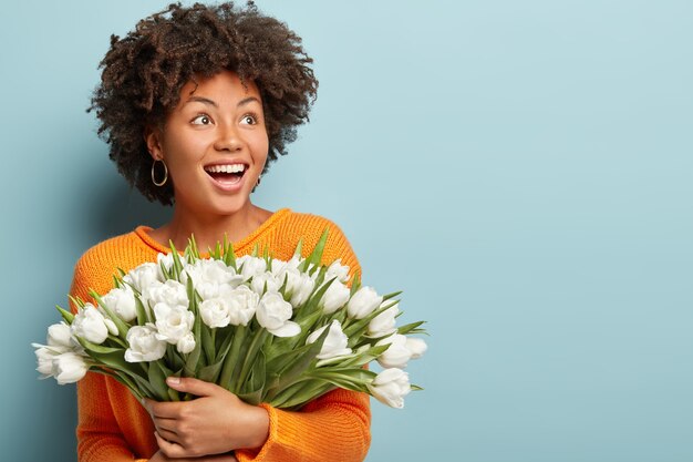 Mujer joven con cabello rizado con ramo de flores blancas