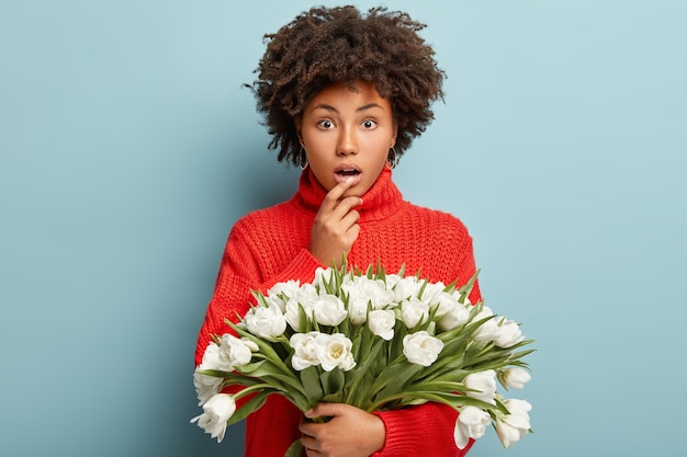 Mujer joven con cabello rizado con ramo de flores blancas