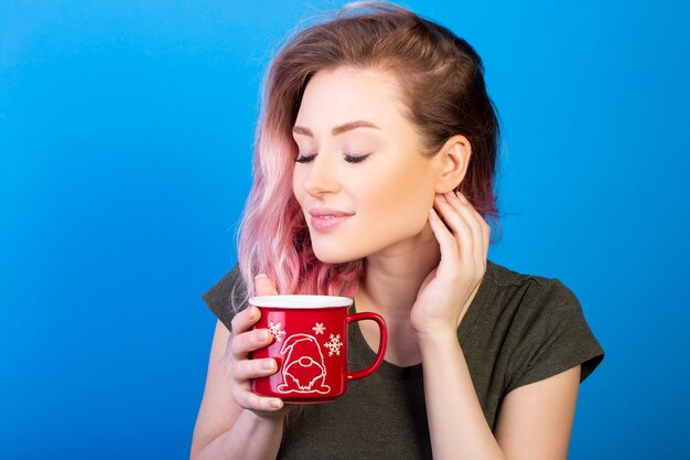 Mujer joven con cabello rosado disfrutando de su taza de té