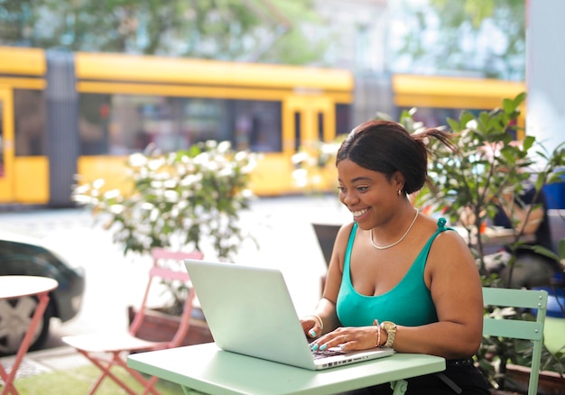 mujer joven en un café al aire libre usa una computadora