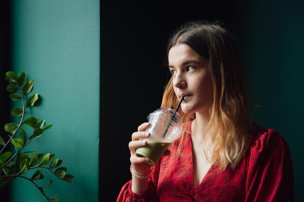 Una mujer joven en un café bebe un café con leche verde